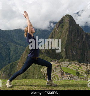 Junges Mädchen tun Krieger 1 Pose mit Die verlorene Stadt der Inkas im Hintergrund, Machu Picchu, Cusco Region, Peru Stockfoto