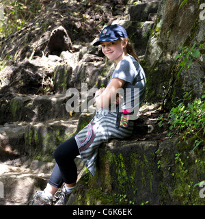 Junges Mädchen sitzt auf Schritte in die verlorene Stadt der Inkas, Machu Picchu, Cusco Region, Peru Stockfoto