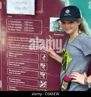 Teenager-Mädchen stehen neben einer Informationstafel Wayna Picchu, die verlorene Stadt der Inkas, Machu Picchu, Region Cusco, Peru Stockfoto