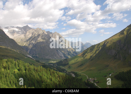 ein Tal in den Alpen mit Wald Wolken und hohen Bergen im Hintergrund Stockfoto