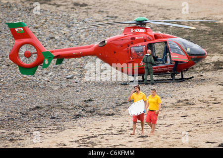 RNLI Rettungsschwimmer vorbei an Wales Air Ambulance Helikopter bei Langland Bucht in der Nähe von Swansea. Stockfoto