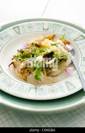 Chicorée mit Tahini-Sauce und knusprigen Zwiebeln Stockfoto