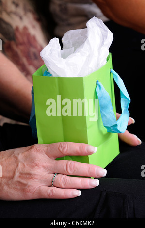 Reife Frau die Hände halten einen Geburtstag Geschenk-Tasche Stockfoto