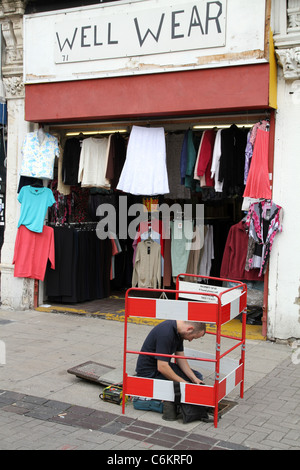 Telefonzentrale-Techniker reparieren Linien außen Second-Hand Bekleidungsgeschäft in Leyton, London, UK Stockfoto