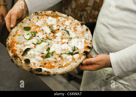 Person halten frisch zubereitete pizza Stockfoto