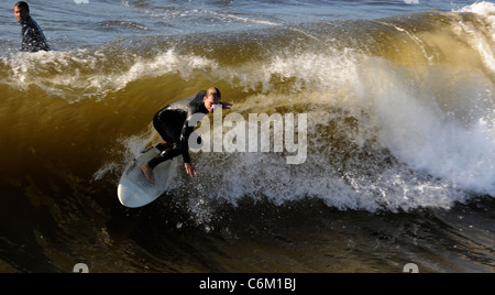 Surfer aufsteht auf einer Welle. Die Welle dreht sich mit Schaum und Spritzer. Stockfoto