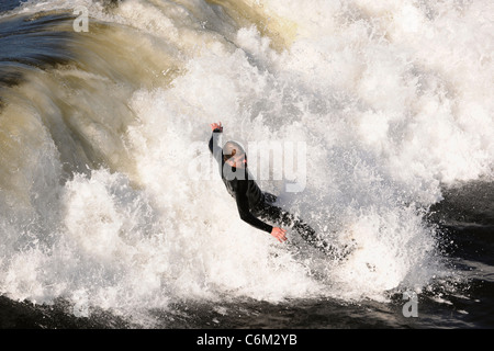 Surfer aufsteht auf einer Welle. Die Welle dreht sich mit Schaum und Spritzer. Stockfoto