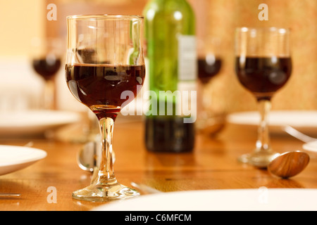 Esstisch mit einer Flasche Wein und Gläser mit Rotwein gefüllt Stockfoto