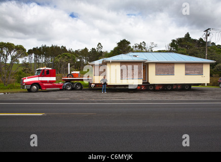 Ein verschiebbarer Haus geschleppt auf einem Anhänger an einen anderen Speicherort. In einem Parkstreifen abgestellt. Auckland Region. North Island, Neuseeland Stockfoto