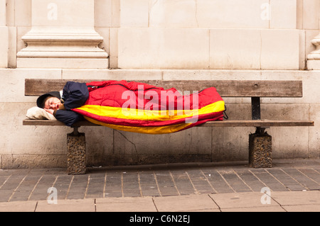 Ein Obdachloser schlafen rau auf einer Bank in Norwich, Norfolk, England, Großbritannien, Uk Stockfoto