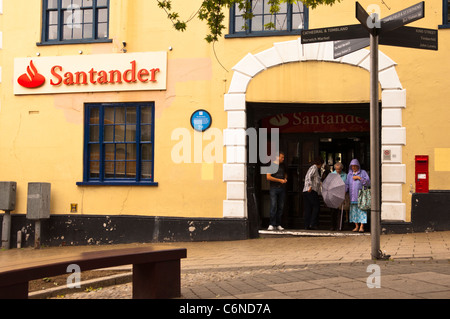 Die Santander Bank mit Menschen Zuflucht vor dem Regen in Norwich, Norfolk, England, Großbritannien, Uk Stockfoto