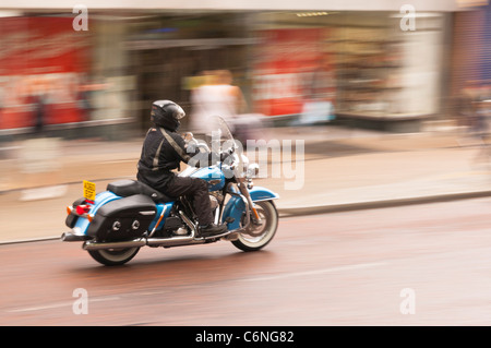 Ein Mann auf einem Motorrad Fahrten durch die Stadt und zeigt absichtlich Bewegungsunschärfe in Norwich, Norfolk, England, Großbritannien, Uk Stockfoto