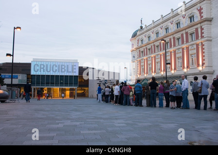 Linie von Menschen warten draußen Crucible Theatre und Lyceum Theatre an der Dämmerung, Tudor Platz Sheffield City Centre, UK Stockfoto