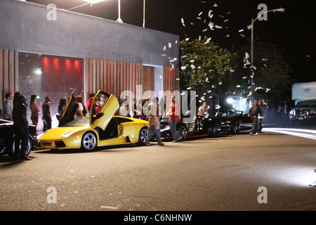 Dollar-Noten sind in der Luft neben luxuriösen Autos vor einem Nachtclub, am Set des neuen Flo Rida Videos in Hollywood geworfen. Stockfoto