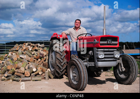 Ein junger Landwirt im Bild mit seinem roten Massey Ferguson Traktor, Dorset, Großbritannien Stockfoto