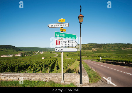 Schild am Eingang zum Dorf Meursault mit Weinbergen und das Dorf von Auxey-Duresses in der Ferne Stockfoto