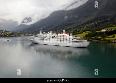 Das Kreuzfahrtschiff vor Anker Boudicca in den Fjords in Olden, Stryn, Norwegen mit seinem zarten Boot nähert sich. Stockfoto