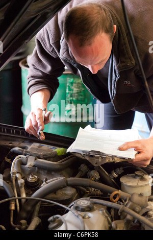 Garage Mechaniker überprüfen die Unterseite eines Autos während einer TÜV-Prüfung im Vereinigten Königreich Stockfoto