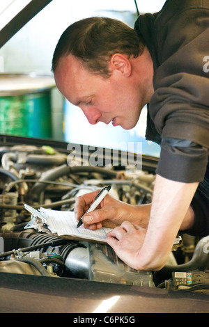 Garage Mechaniker überprüfen die Unterseite eines Autos während einer TÜV-Prüfung im Vereinigten Königreich Stockfoto