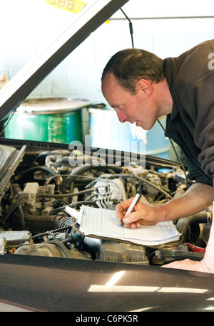 Garage Mechaniker überprüfen die Unterseite eines Autos während einer TÜV-Prüfung im Vereinigten Königreich Stockfoto