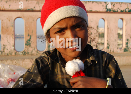 Ein armes Mädchen verkauft Weihnachtsmann-Mützen zum Zeitpunkt von Weihnachten (Indien) Stockfoto