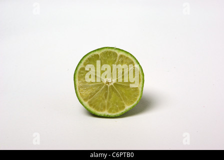 Eine halbe Limette sitzt auf einem weißen Hintergrund. Stockfoto