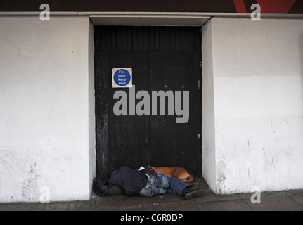 Sleeping Rough oder rauen Schwellen Stadtzentrum Brighton - Mann und sein Hund sackte schlafend in einem Hauseingang in West Street Brighton UK Stockfoto