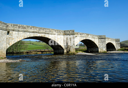 Alte Steinbrücke überspannt den Fluß Wharfe im Burnsall, North Yorkshire Stockfoto