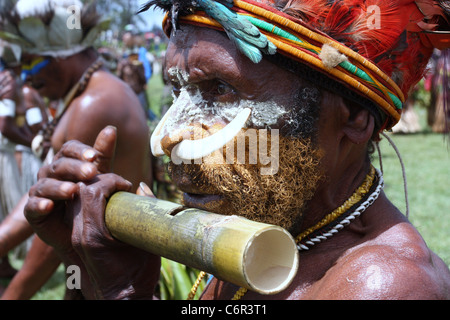 Stammesangehörige in Papua-Neu-Guinea spielen eine Bambusflöte Stockfoto