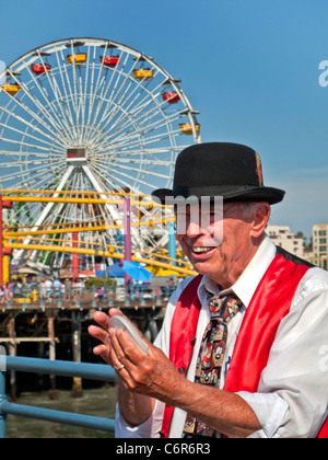 Ein älterer Magier mischt Karten für sein Publikum im Vergnügungspark am Santa Monica Pier. Stockfoto