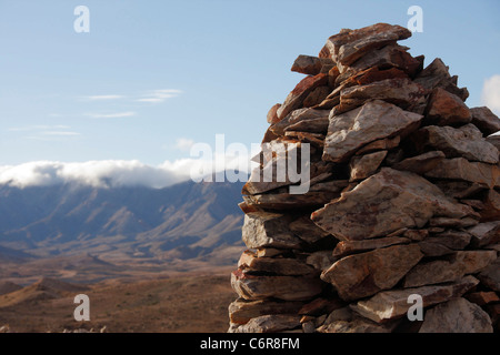 Halbwüstenartige Landschaft mit Wolken über den Rosuintjieberg-Bergen in der Ferne und Stein Haufen im Vordergrund. Stockfoto