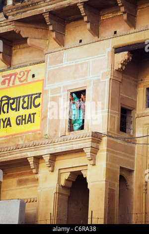Zwei Frauen schauen aus dem Fenster eine Ghat die Fronten des Ganges in Varanasi, Indien im Staat Uttar Pradesh Stockfoto