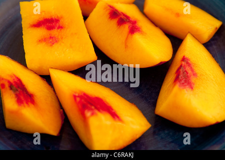 Nektarine / Nektarinen in Stücke - bereit, als schnelles und gesundes Obst Snack auf einem dunklen blau Teller Essen gehackt. Stockfoto