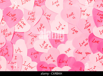 Botschaften der Liebe, die auf rosafarbenem herzförmigem Klebezettelschrieb stehen Stockfoto