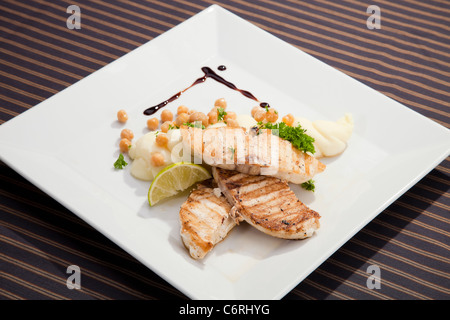 Gegrillte Butter Fisch w Kartoffel Püree Erbsen und Zitrone Stockfoto