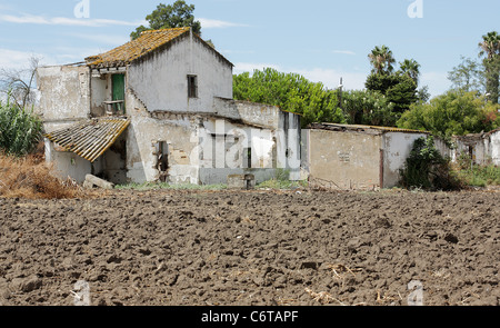Zweistöckiges Landhaus in Schutt und Asche am Fuße eines Feldes ohne Aussaat Stockfoto