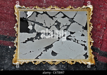 Antike goldene Bilderrahmen mit Glasscherben auf schmutzigen Lappen Hintergrund. Stockfoto