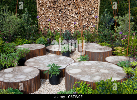 Ein wildlebender Garten mit kreisförmig angehobener Terrasse, Steinpflaster, gepflasterten und insektenfreundlichen Hotel Motel Wall Fence UK Stockfoto