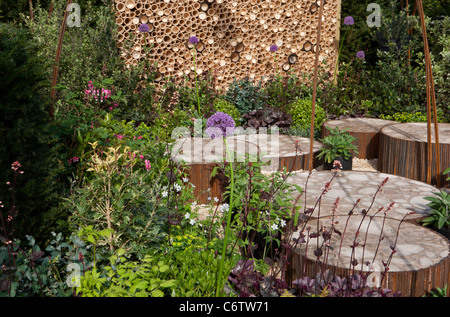 Ein wildlebender Garten mit kreisförmig angehobener Terrasse, Steinpflaster, gepflasterten und insektenfreundlichen Hotel Motel Wall Fence UK Stockfoto