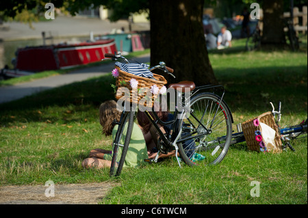 Neben den Fluss Cam in Cambridge eine altmodische Fahrrad mit Korb auf Vorderseite mit Blumen geschmückt. Stockfoto