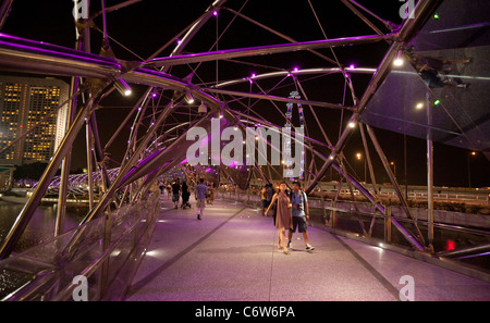 Menschen zu Fuß entlang der modernen Helix-Brücke mit dem Singapore Flyer im Hintergrund, die Marina, Singapur Asien Stockfoto