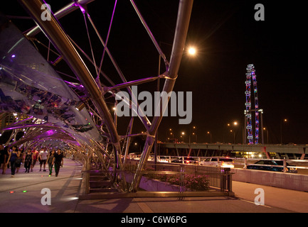 Menschen zu Fuß entlang der modernen Helix-Brücke mit dem Singapore Flyer im Hintergrund, die Marina, Singapur Asien Stockfoto