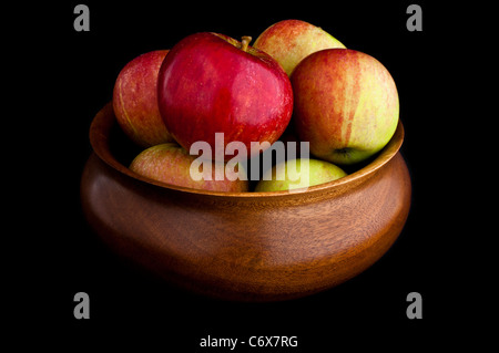 Frische Äpfel in einer Holzschale auf einem schwarzen Hintergrund. Stockfoto