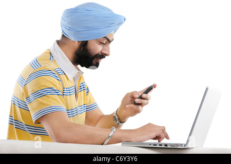 Sikh Mann mit Handy und laptop Stockfoto