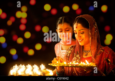 Mutter ein Tablett mit Diyas zu halten, während ihre Tochter blickt auf Stockfoto