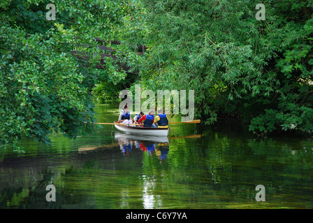 Familie im Ruderboot vorbei durch Bäume auf friedliche Stream in Cookham Stockfoto