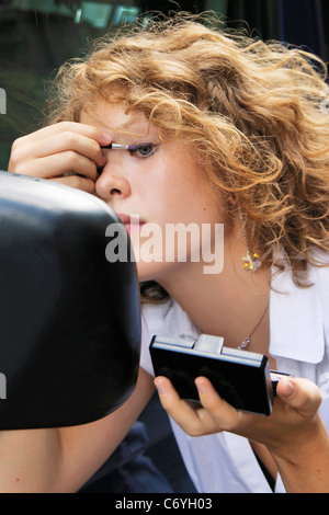 Frau beim Schminken in Autospiegel Stockfoto