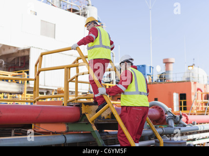 Arbeitnehmer, die klettern über Rohre auf Bohrinsel Stockfoto