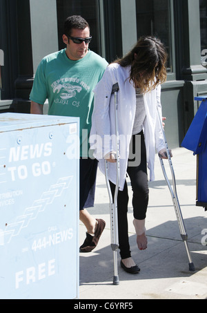 Adam Sandler hilft seiner Frau Jackie, als sie auf ihre Krücken geht, nach dem Mittagessen. Los Angeles, Kalifornien, USA - 13.03.10 Stockfoto