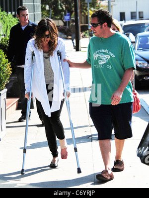 Adam Sandler hilft seiner Frau Jackie, als sie auf ihre Krücken geht, nach dem Mittagessen. Los Angeles, Kalifornien, USA - 13.03.10 Stockfoto